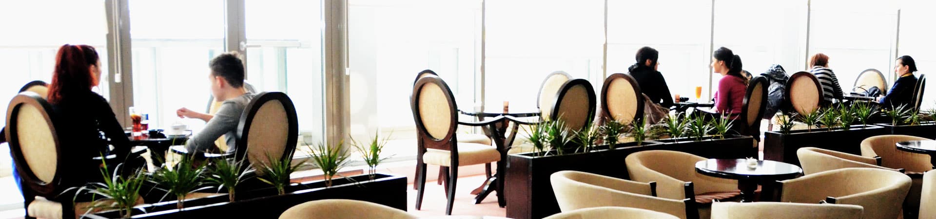Mese lângă ferestrele panoramice ale cafenelei Business Time Coffee